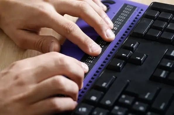 Male hand navigates website using braille keyboard